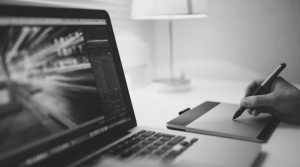 man designing on pad next to laptop