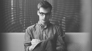 man in glasses writing in book